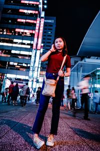 Full length of woman standing on city street at night