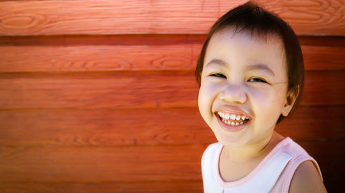 Portrait of smiling girl against wooden wall