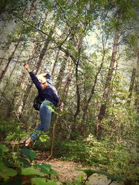 Low angle view of man jumping in forest