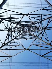 Low angle view of electricity pylon against clear blue sky