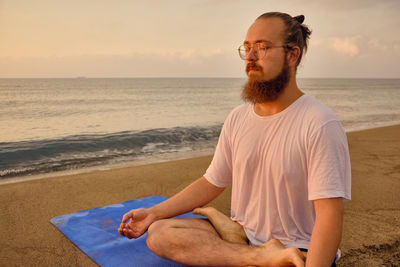 Man practices yoga meditation sitting in padmasana during sunrise. man sits in lotus position