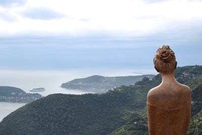 Statue on mountain by sea against sky