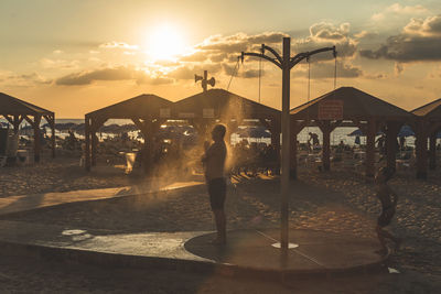 Man standing on beach against sky during sunset