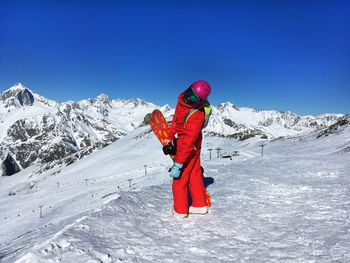 Person on snowcapped mountain against clear blue sky