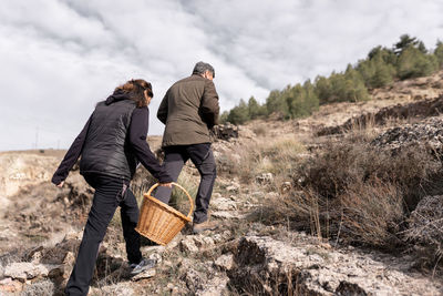 A couple is walking in the nature with a basket to collect mushrooms