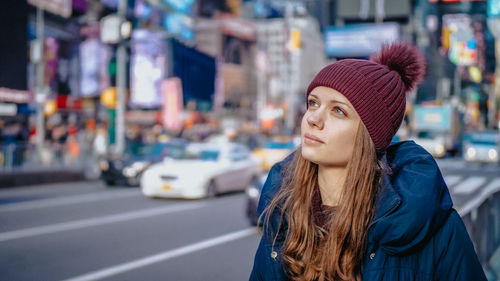 Portrait of beautiful young woman wearing hat on street in city