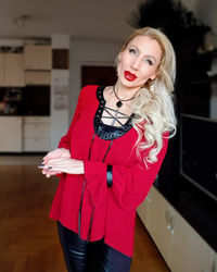 Portrait of woman standing against red wall