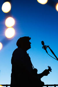 Low angle view of silhouette man against illuminated clear blue sky