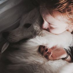 High angle view of woman lying with dog on bed