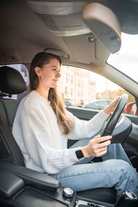 Young woman using mobile phone while sitting in car