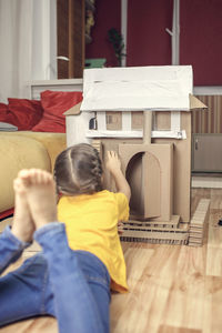 Rear view of a girl sitting on table at home