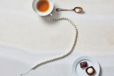Still life of necklace, tea cup, chocolates