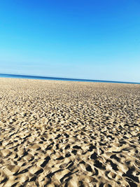 Scenic view of beach against clear blue sky