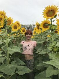 Portrait of young woman standing by sunflower