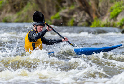 Young man kayaking in river