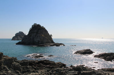 Rock formation in sea against clear sky