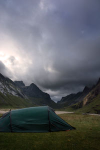 Tent on grass by mountains against sky
