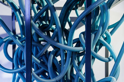 Close-up of blue tangled cables against wall