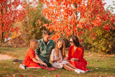 Rear view of people sitting on autumn leaves