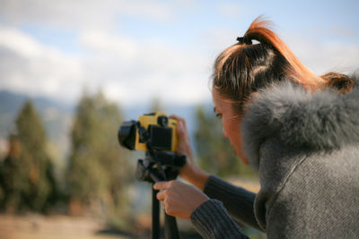 Close-up of woman photographing against landscape