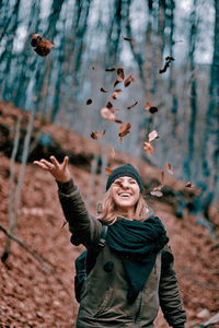 Portrait of young happy girl throws leaves in the air