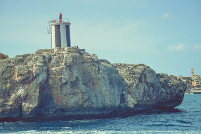 Lighthouse by sea against sky