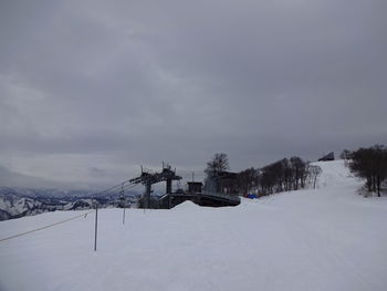 Snow covered house by building against sky