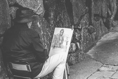 Rear view of man sitting on street against trees