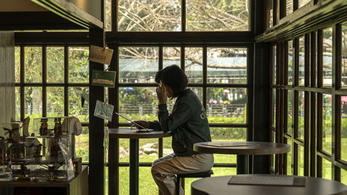 Woman looks at the book before windows