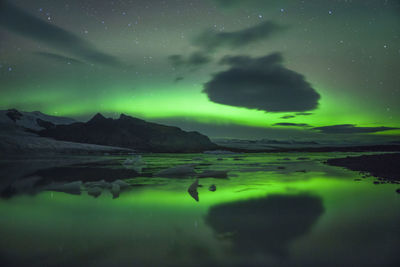 Scenic view of aurora borealis over lake against sky at night