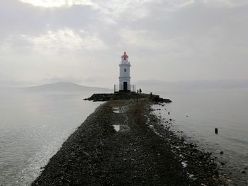 Lighthouse by sea against sky