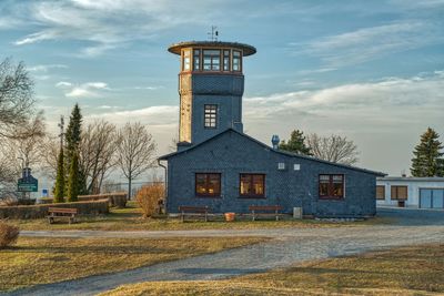 House on field by building against sky