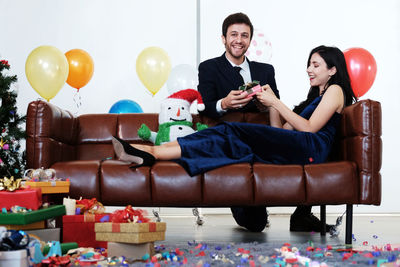 Young couple sitting on balloons at table