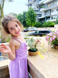 Portrait of young woman standing against building