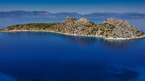 Panoramic view of sea and island mountains against blue sky