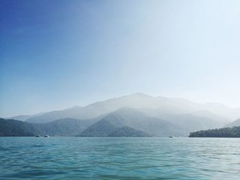 Scenic view of sea and mountains against blue sky