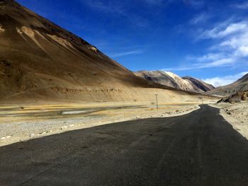 Road by mountains against sky