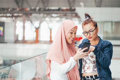 Smiling women sharing smart phone