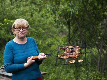 Smiling woman with arms raised on barbecue