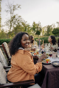Portrait of smiling woman sitting at dining table during party in back yard