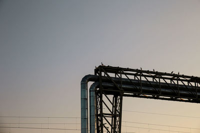 Low angle view of silhouette crane against clear sky