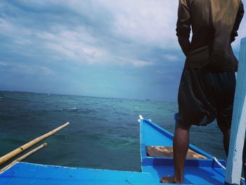 Low section of men standing on boat sailing in sea