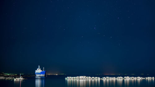 Ship sailing on sea against sky at night