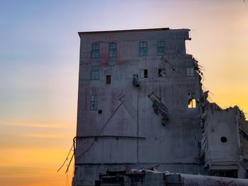 Low angle view of abandoned building against sky during sunset