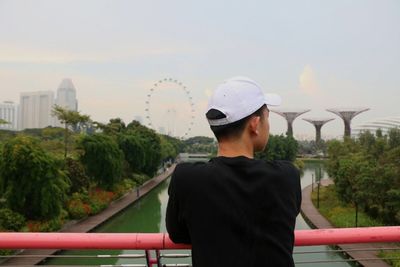 Rear view of man standing on bridge at gardens by the bay against sky