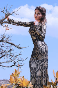 Beautiful woman looking away while standing against sky