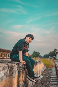 Rear view of boy looking at camera against sky