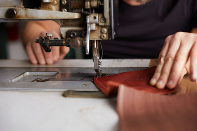 Midsection of man using sewing machine