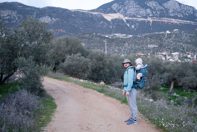 Man hiking in mountains,carrying baby in bacpack,sling,carrier.family travelling,trips,lifestyle