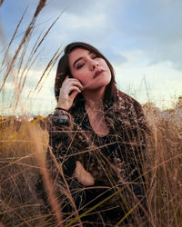 Beautiful young woman sitting amidst plants on land